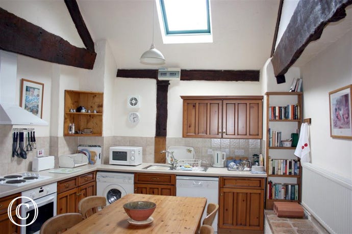 The spacious kitchen is bright, very well-equipped and offers a dining table and chairs at the centre